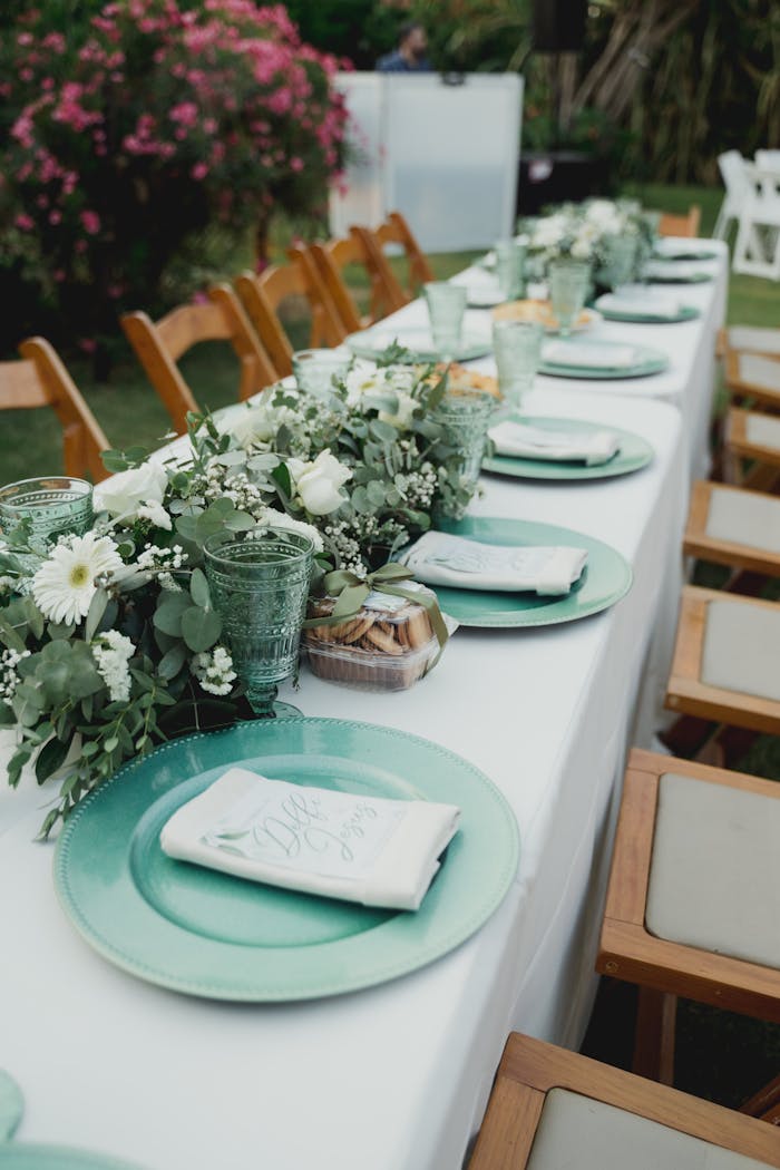 Chic outdoor dining setup featuring a floral centerpiece and elegant tableware on a long table.