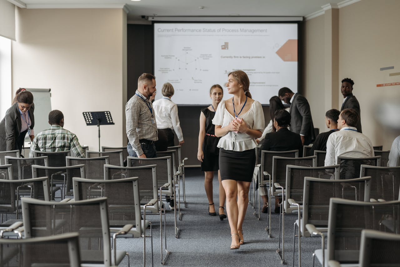 Professionals at a business conference engage before a presentation in a modern office.